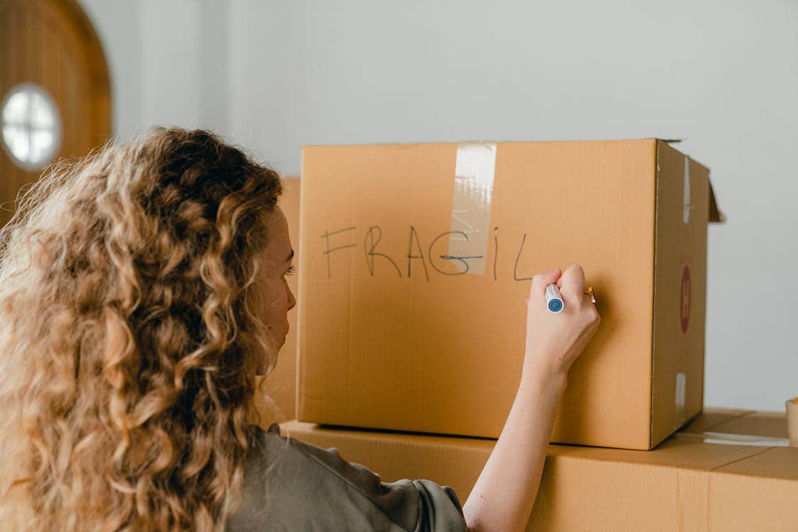 Eine Frau packt zerbrechliche Gegenstände in einen Karton, um sie zu lagern.
